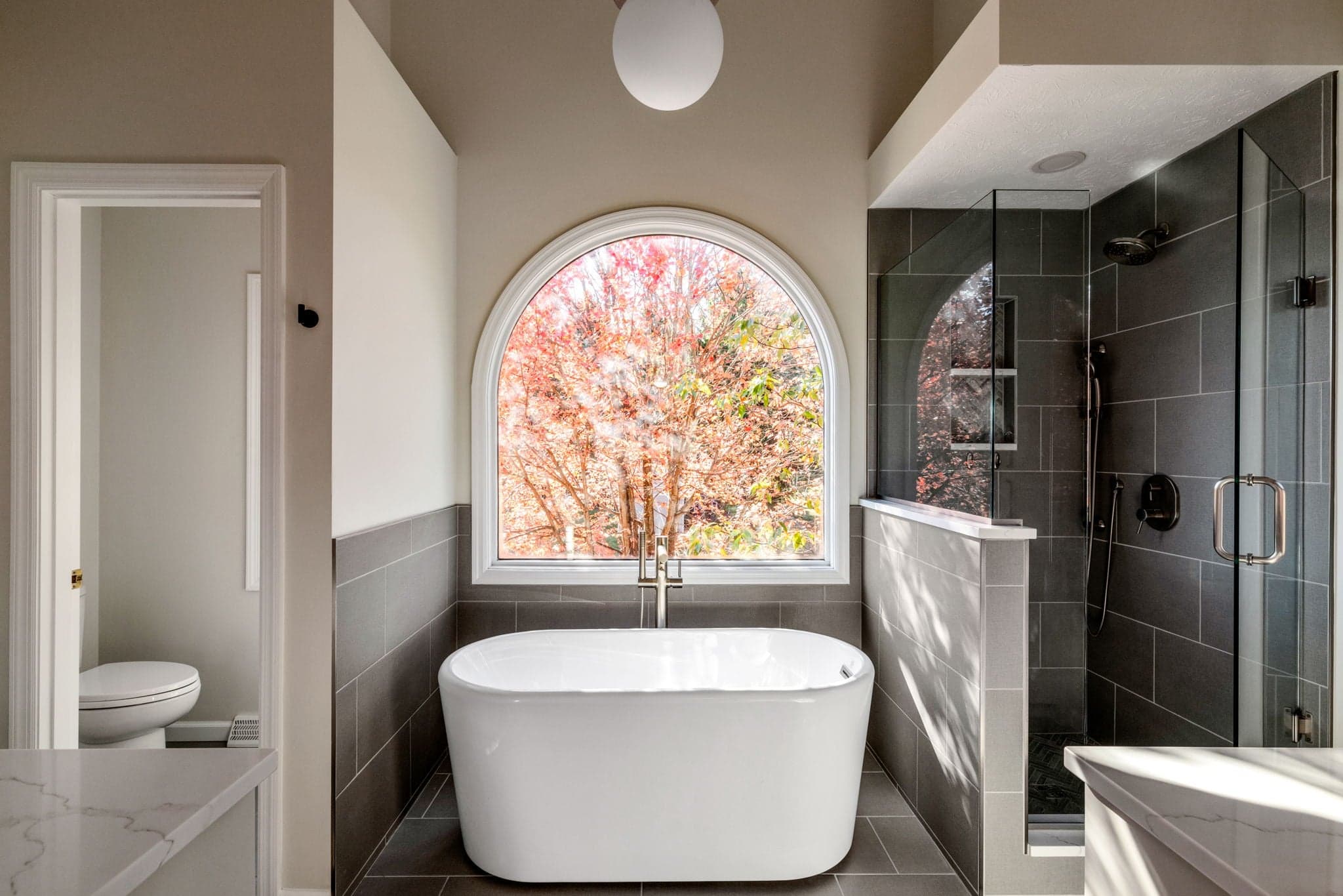 Primary bathroom renovation with an arched window and freestanding tub on Breezewood Drive in Canonsburg, PA, built by Integrated Contracting & Renovations